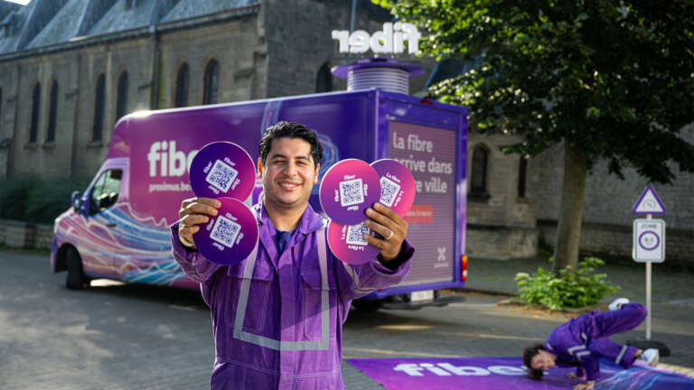 Proximus field activation with a brand ambassador handing out materials in front of a customized van