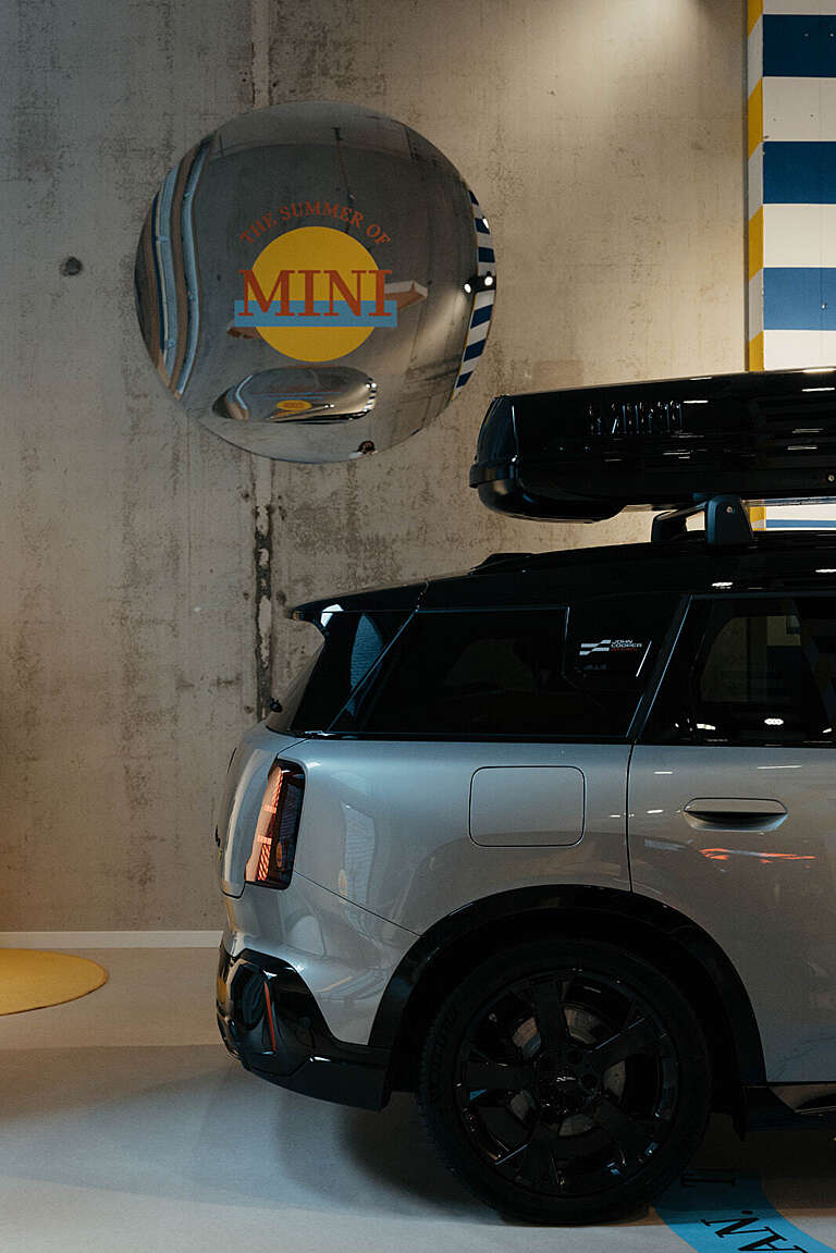 A silver MINI car displayed under a reflective sphere featuring the MINI logo.