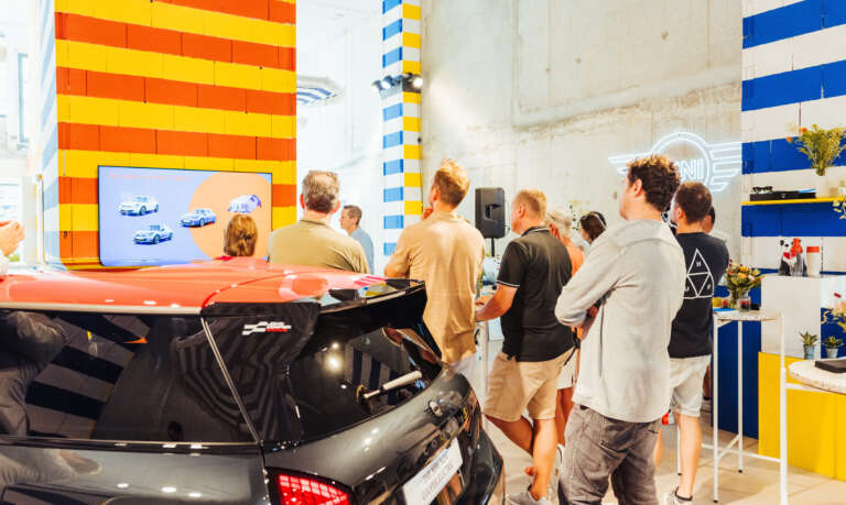 Group of visitors attending a MINI models presentation inside a colorful showroom.