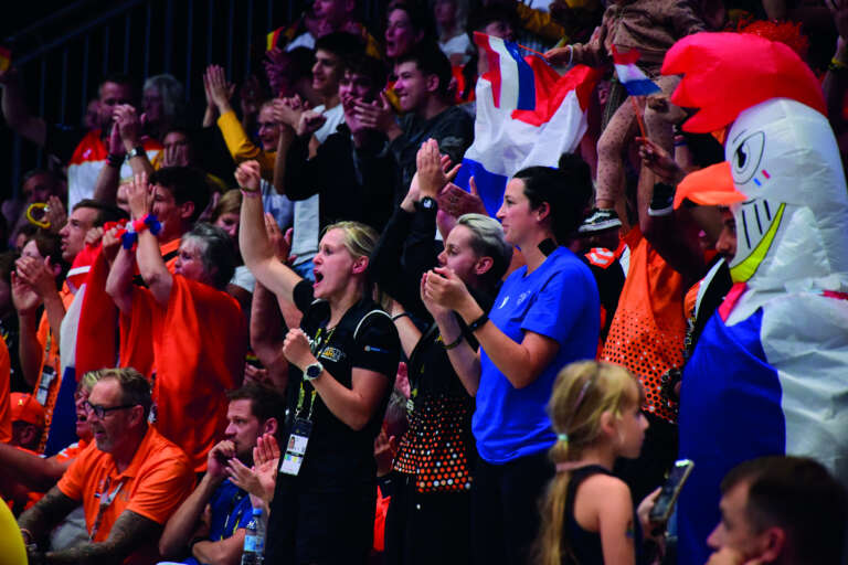 Supporters enthousiastes dans les tribunes, applaudissant les athlètes avec ferveur.