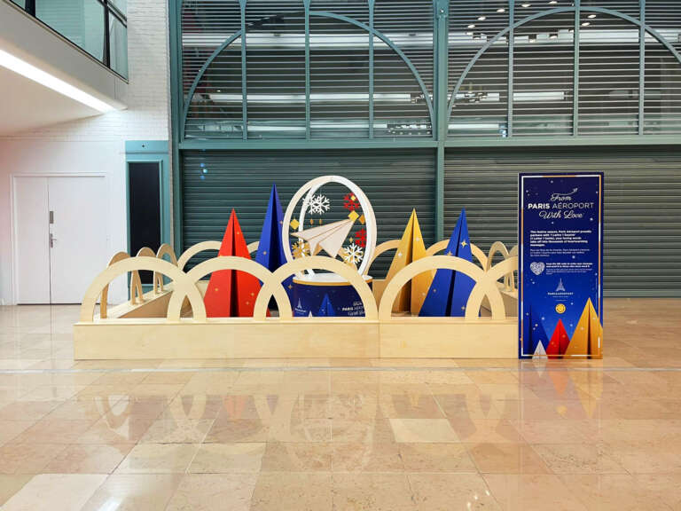 Colorful wooden and paper installation in the airport featuring a paper plane at its center.
