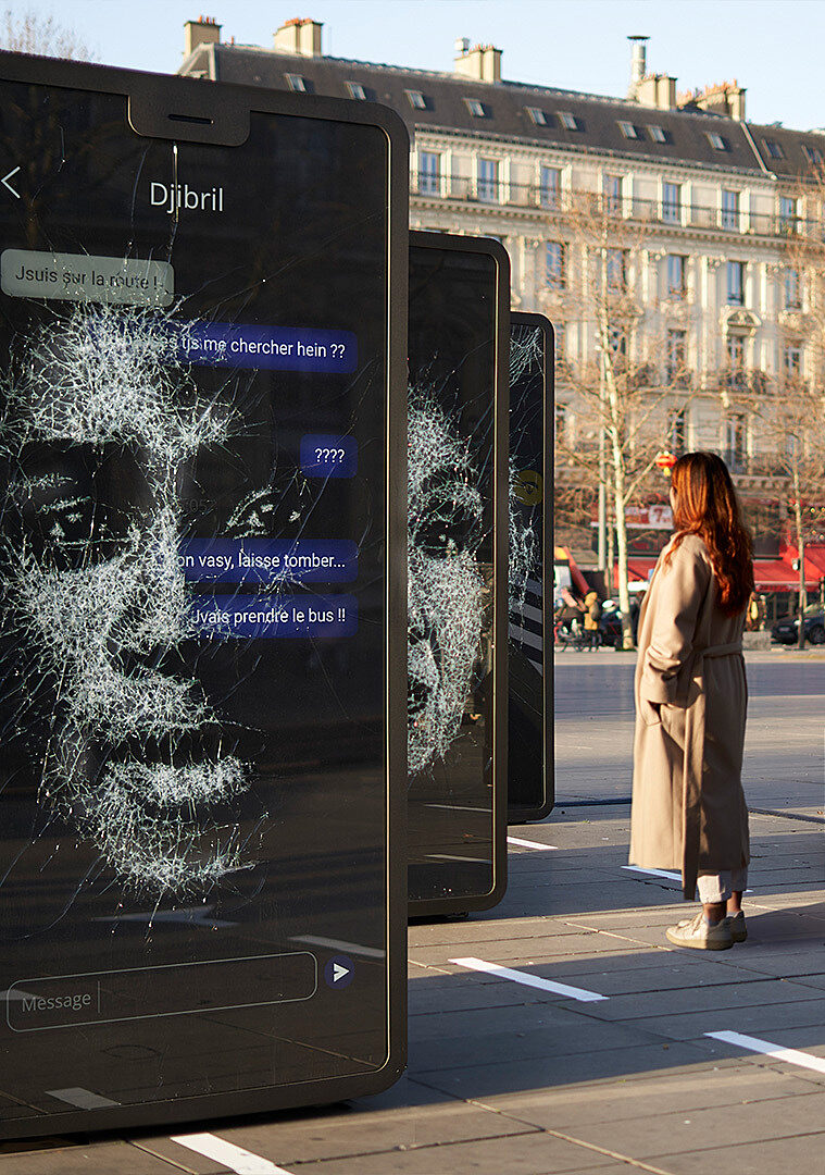 Une femme observe l’exposition “Vies Brisées” sur la place de la République à Paris.