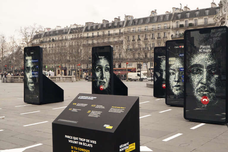 Détail de l’exposition avec les visages et les messages affichés sur de grands téléphones.