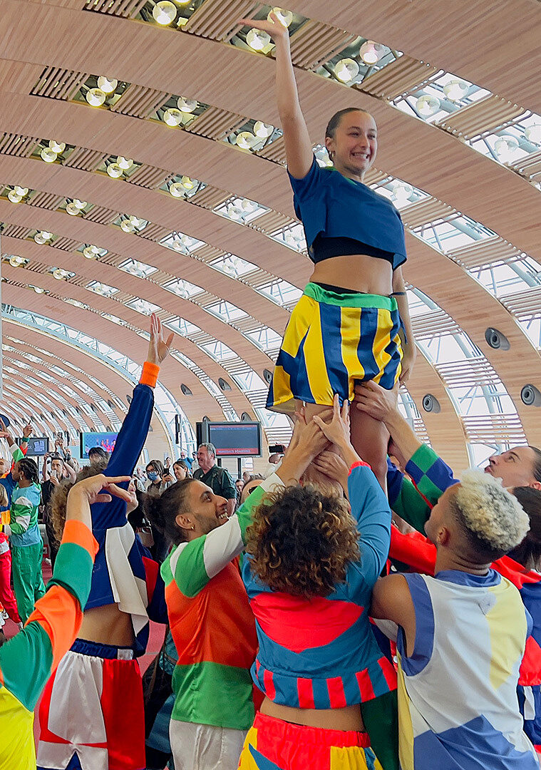 A human pyramid of dancers beneath the large glass ceiling of the terminal.