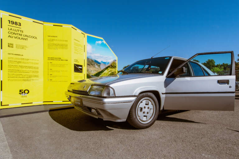 Une Citroën BX grise garée devant un panneau expliquant la lutte contre l’alcool au volant en 1983.
