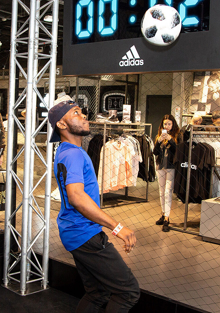 Démonstration de freestyle football avec Adidas, sous le regard du public dans le magasin.