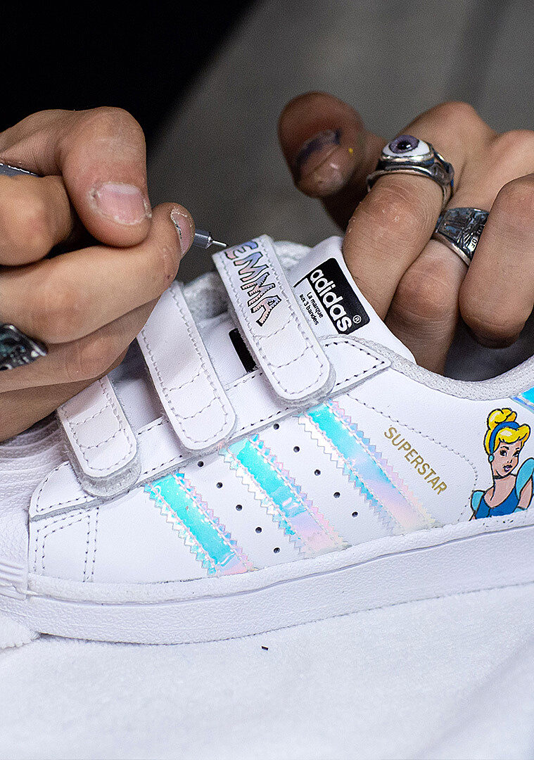 Gros plan sur la personnalisation d’une sneaker Adidas Superstar, décorée à la main.