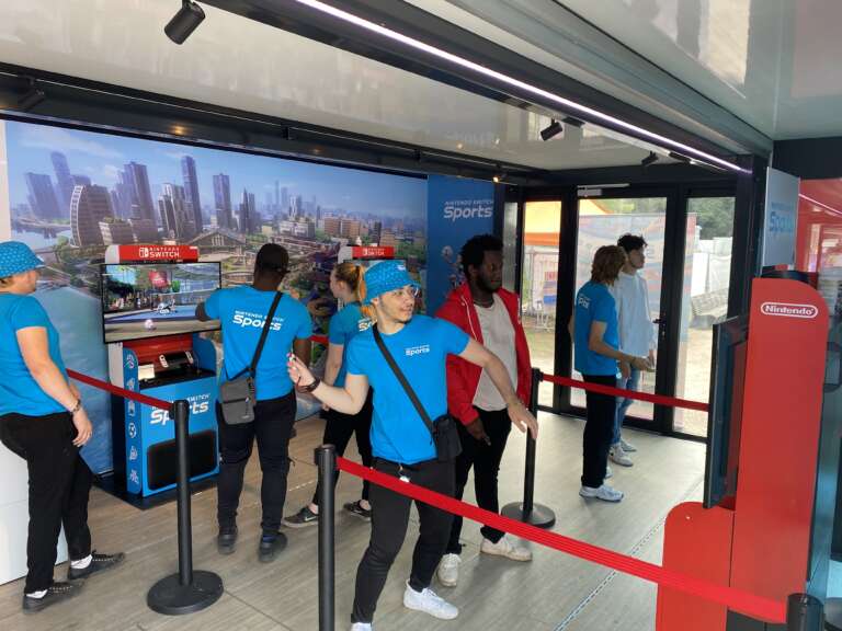 Ambiance à l’intérieur du container Nintendo Switch, avec des animateurs en t-shirt bleu en pleine démonstration.