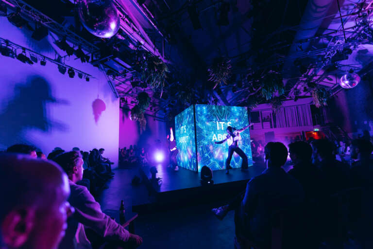 Artistic performance on stage in front of an immersive digital installation, within an innovative B2B event setting