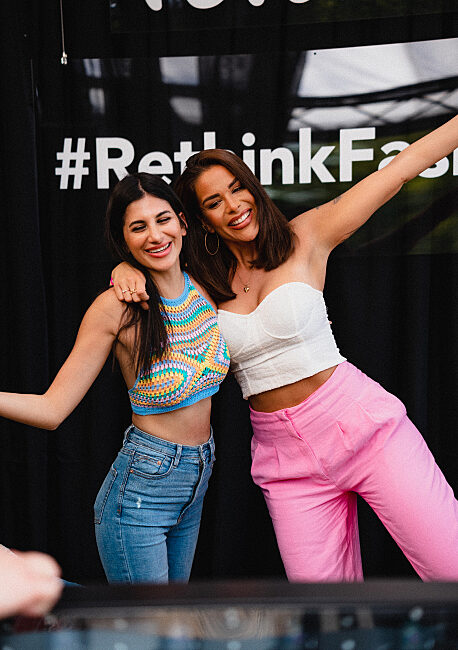 Two influencers posing at a fashion event in front of a branded photo call