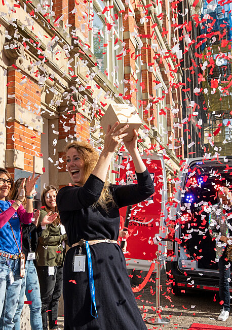 Celebration of a team achievement in front of the office, with confetti and cheering colleagues