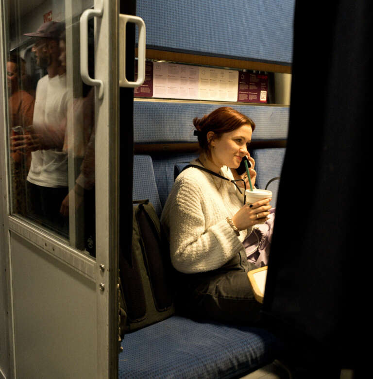 Smiling young woman on a phone call in a train, on her way to an OVAL exchange program
