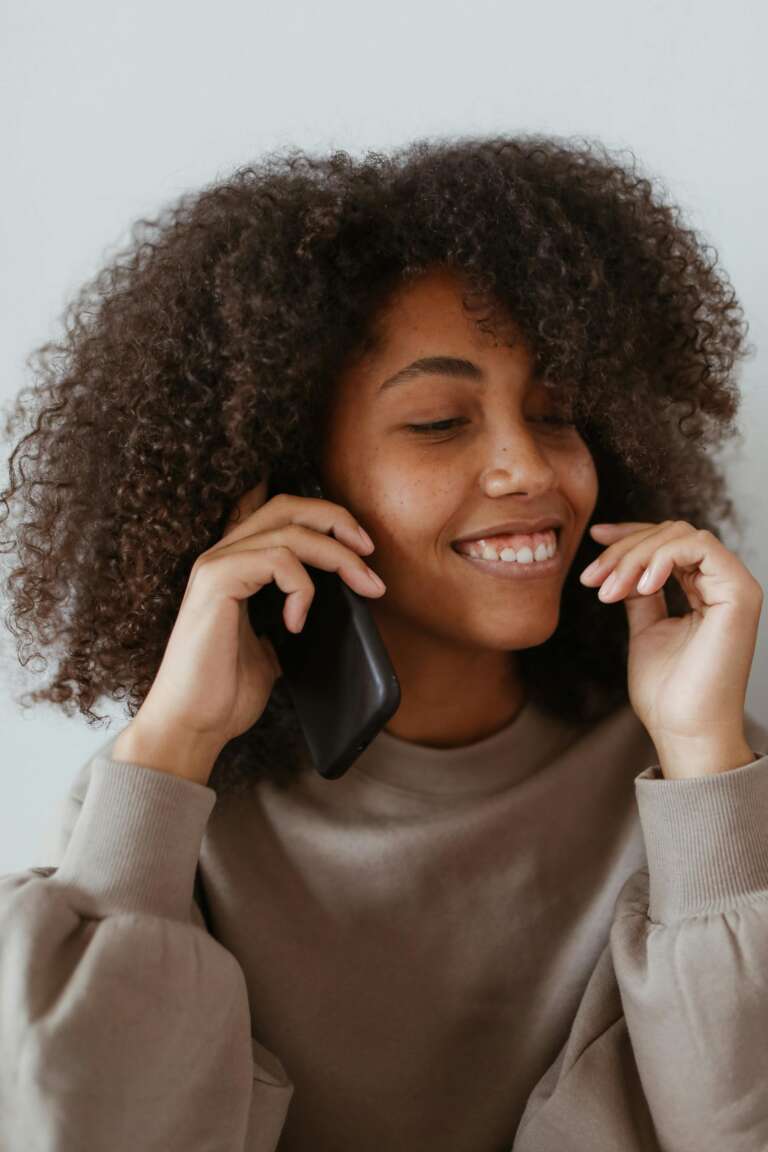 Smiling young woman on a phone call, illustrating the work phone provided by OVAL